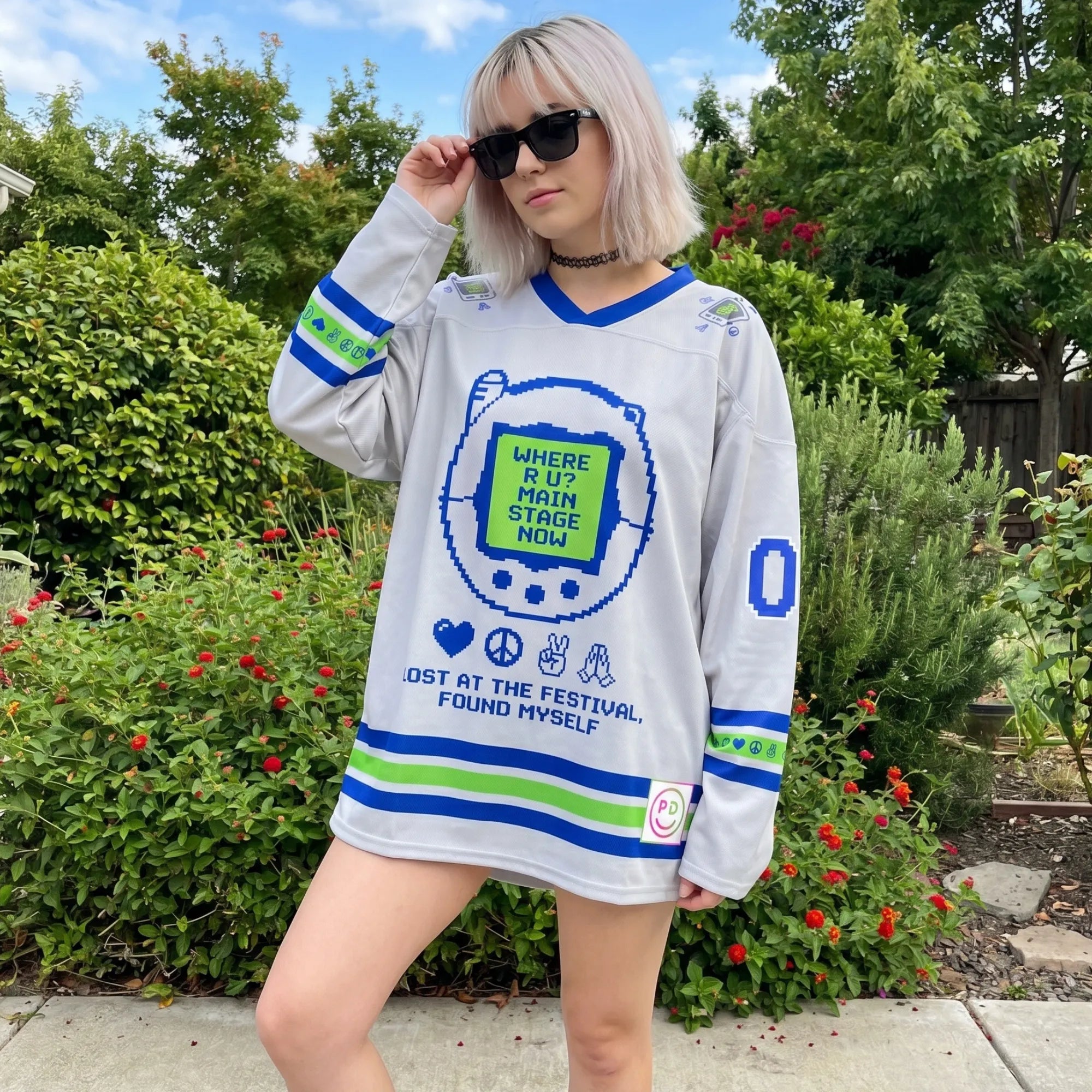 A model outdoors wearing an oversized cute pink moisture-wicking pixel EDM shirt, styled with sunglasses for a daytime festival look.