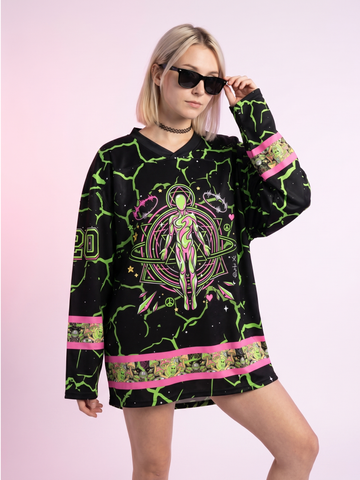 Front view of a blonde woman in sunglasses wearing the oversized neon alien rave hockey jersey.