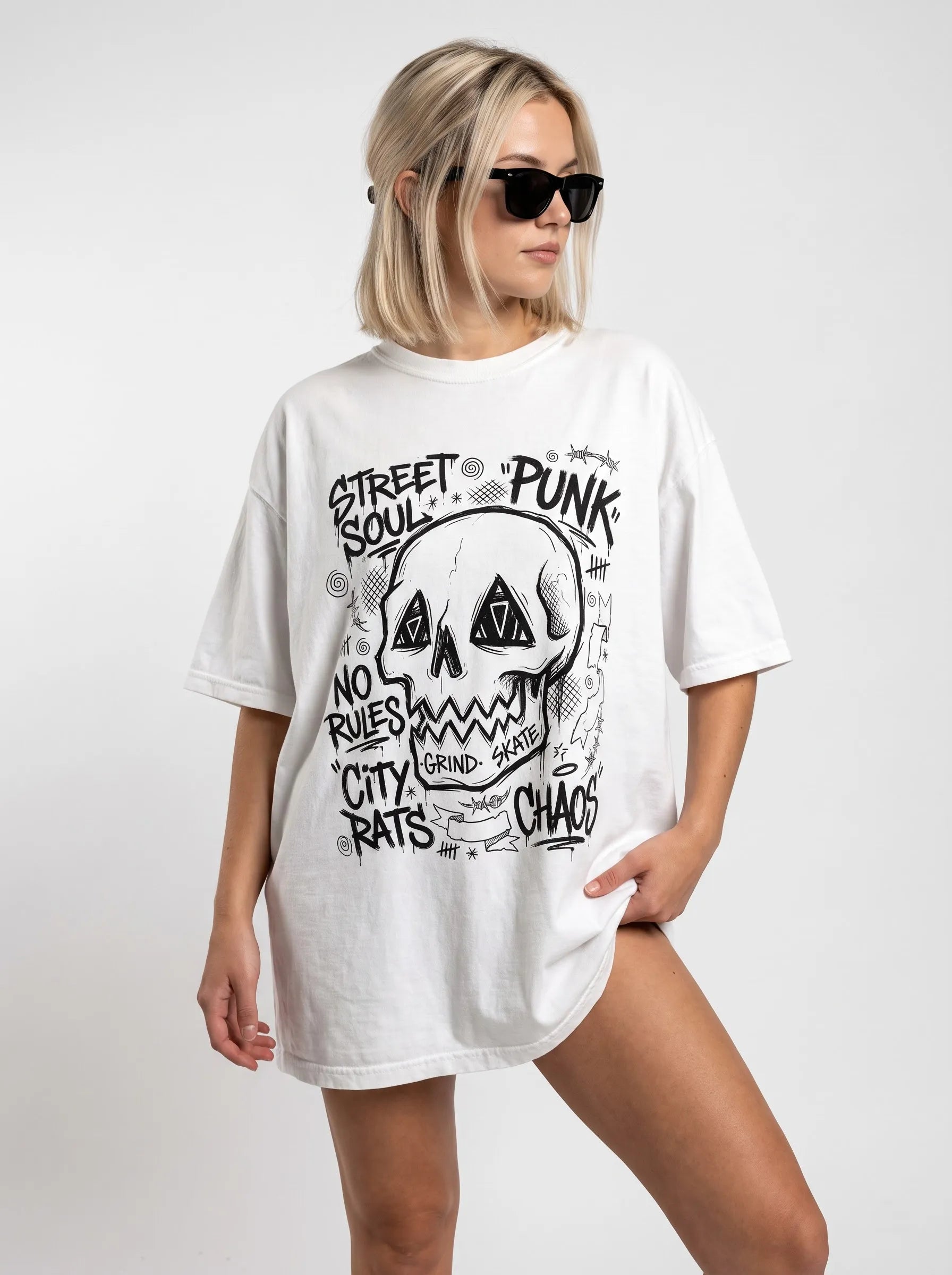 Woman modeling a relaxed fit white punk skull rave t-shirt worn as an oversized festival outfit with black sunglasses.