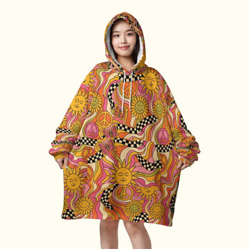 Front view of a woman wearing an oversized trippy blanket hoodie featuring pink and orange retro suns, perfect for cozy rave hippie outfits