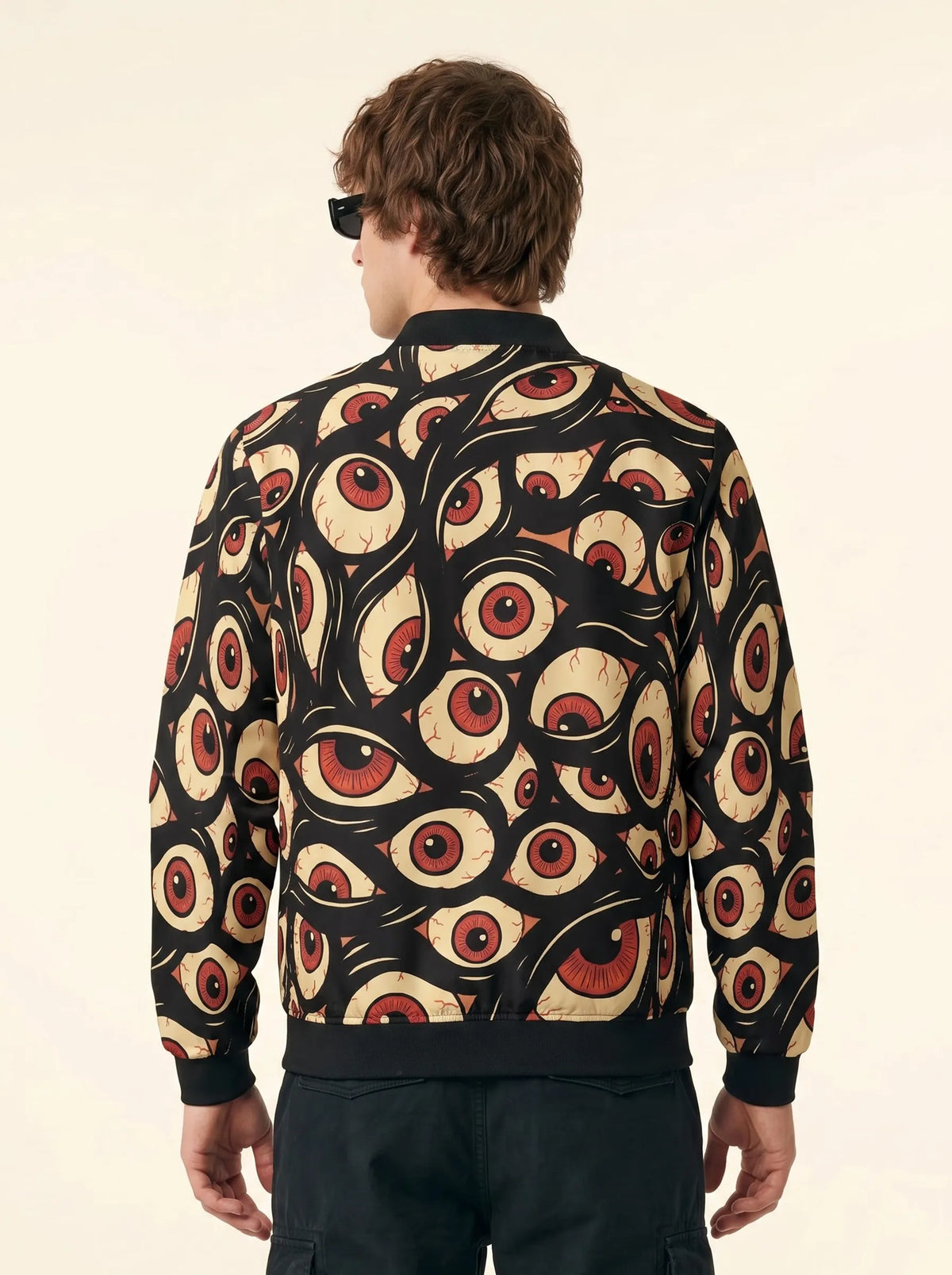 Back view of a model wearing the Trippy Eye Zip Up Rave Bomber, a Halloween jacket with an all-over bloodshot eyeball print.