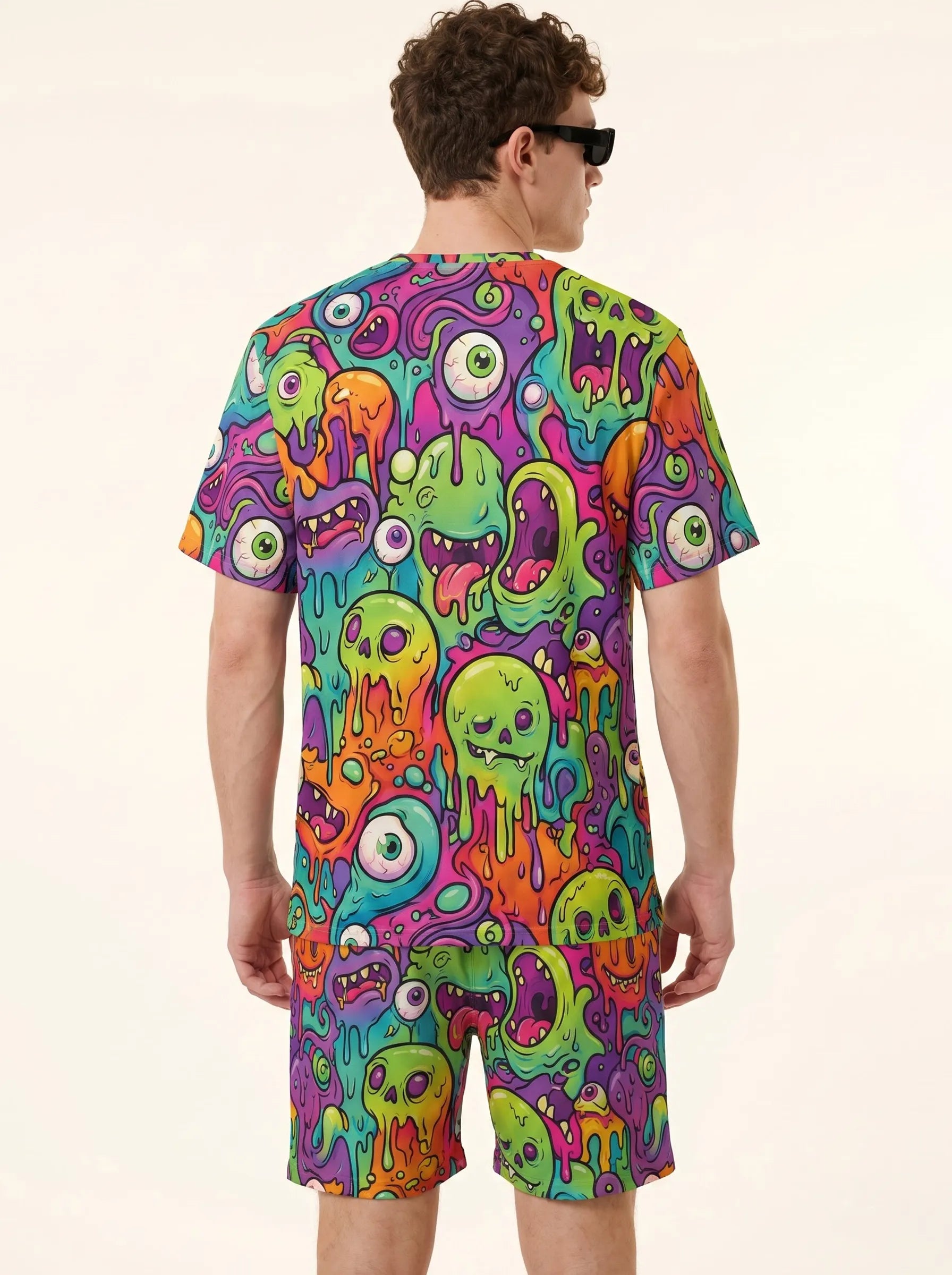 Back view of a male model modeling the Trippy Monster Rave Shorts and matching graphic tee festival outfit.