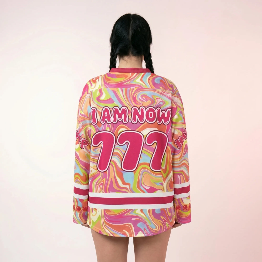A woman wearing the trippy pink rave hockey jersey, featuring a vibrant psychedelic marble pattern and a large melting smiley face with the word "HAPPY?". A relaxed and breathable EDM festival outfit.