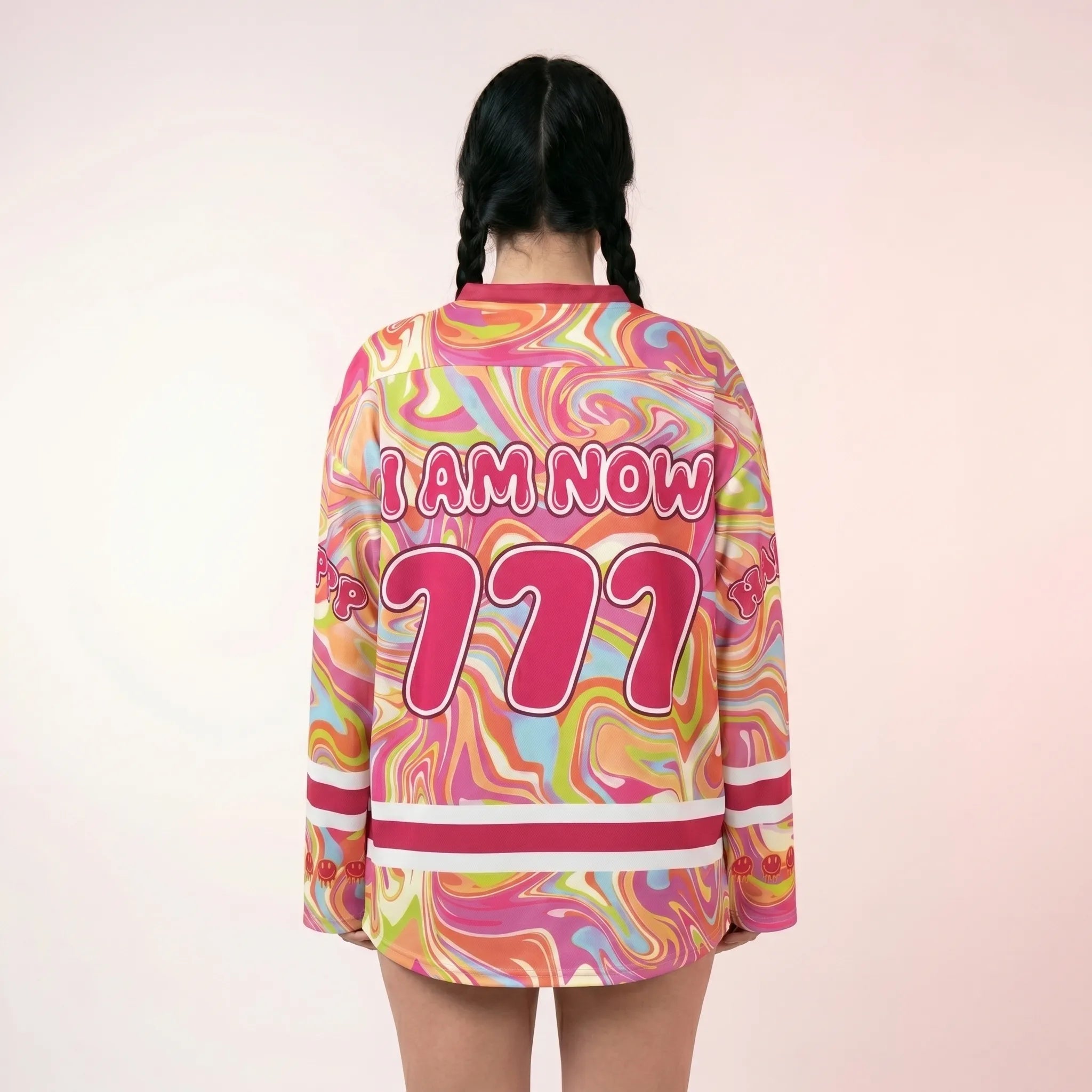 Back view of a woman wearing the trippy pink rave hockey jersey. The oversized EDM festival outfit showcases a liquid swirl pattern and bold "I AM NOW 777" graphic across the back