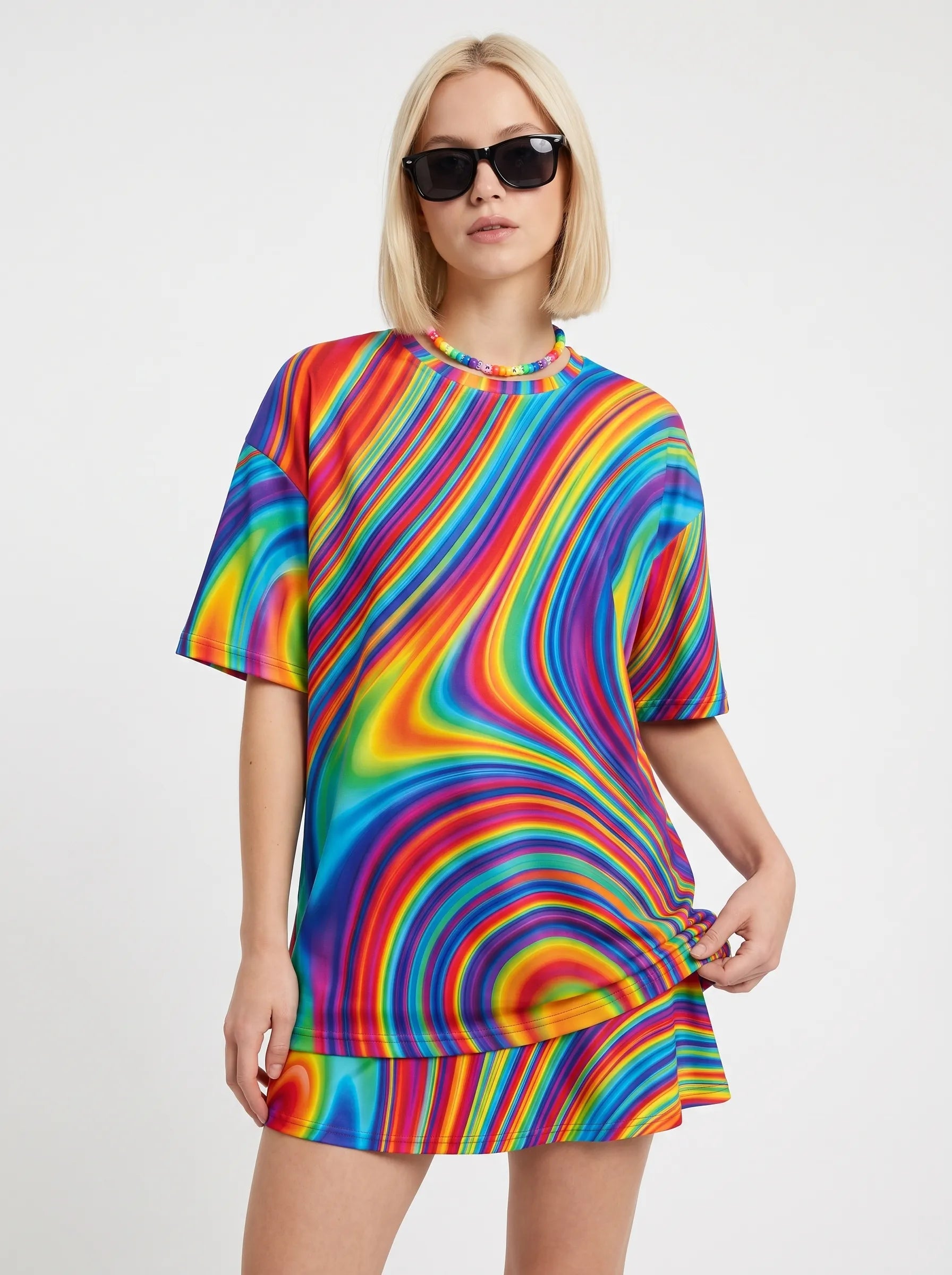Front view of a model wearing the Trippy Rave T Shirt. This fade-proof festival top features a vibrant all-over liquid rainbow swirl pattern, paired with a matching skirt.